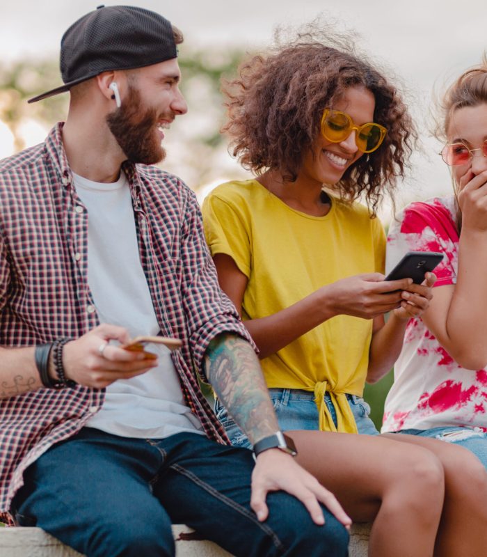happy-young-company-smiling-friends-sitting-park-using-smartphones-man-women-having-fun